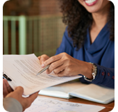 A businessperson hands paperwork to a client. 